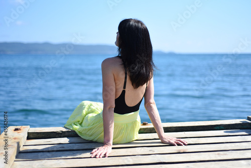 45 years old Russian woman sitting on a pier and looking away against Japanese sea