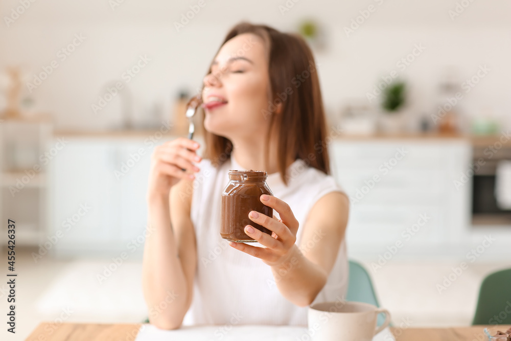 Beautiful young woman eating tasty chocolate paste at home Beautiful young woman eating tasty chocolate paste at home