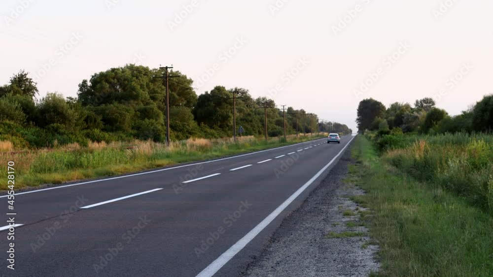 One car drives on a quality asphalt road at sunset. One car drives on a quality asphalt road at sunset.