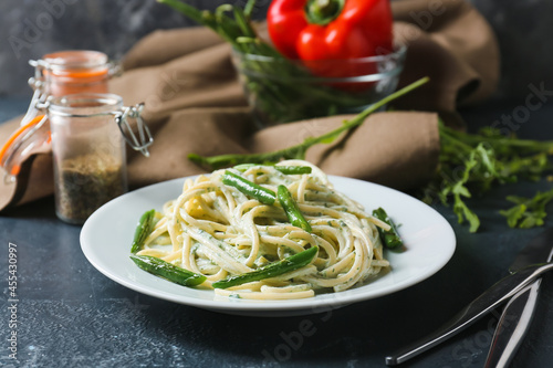 Plate of tasty pasta with green beans on dark background