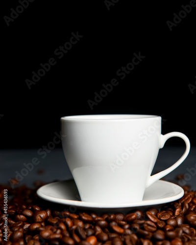 Warm cup of coffee with coffee beans over black background. Coffee time, copy space web design banner.