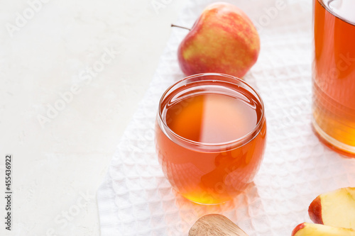 Glass of apple juice on light background