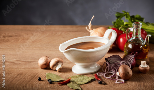 Quadro su tela Gravy boat or pitcher with savory spicy gravy and vegetables