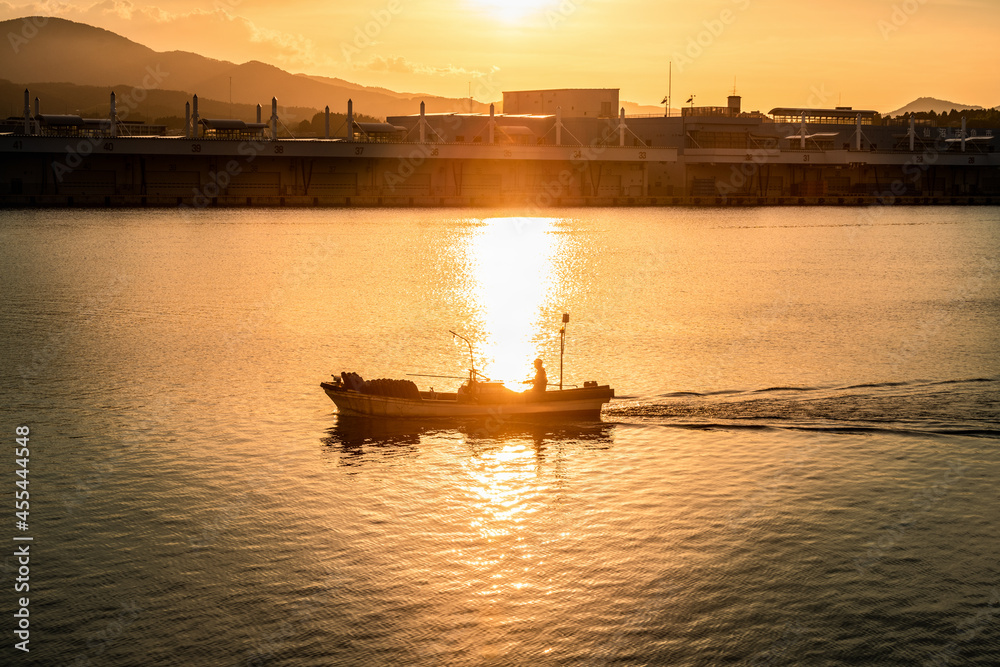 日本　夕焼けの気仙沼漁港を行く漁船