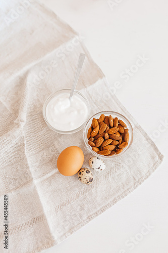 Nuts almonds  sour cream or yogurt  chicken and quail eggs on a linen kitchen towel on a white table. Healthy food and nutrients for proper nutrition of the brain and body concept