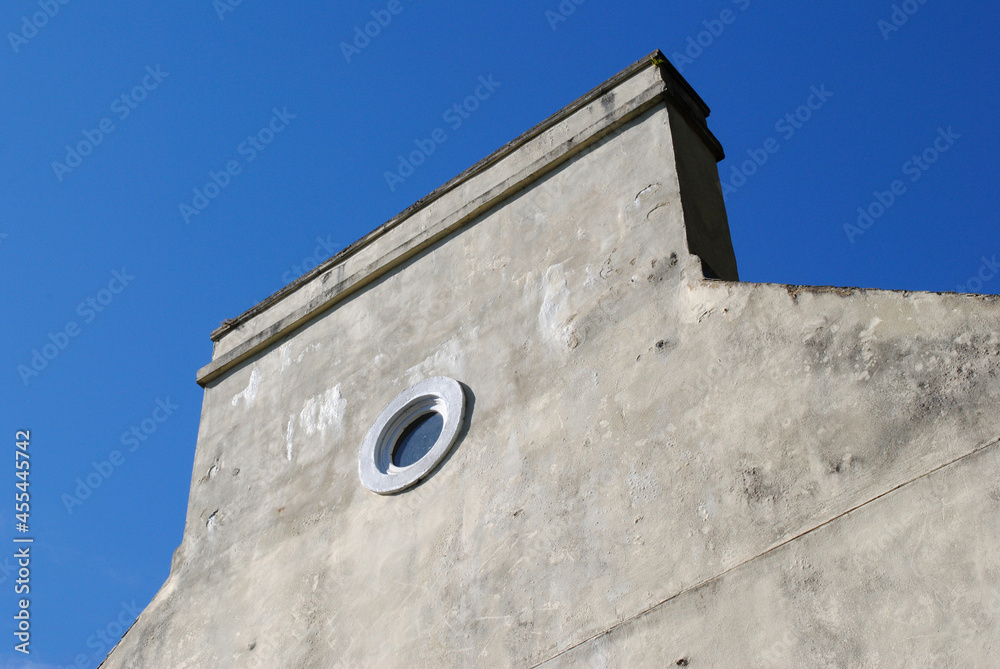 Small Circular Window in Gable Wall of Old House with Chimney Stack & Blue Sky