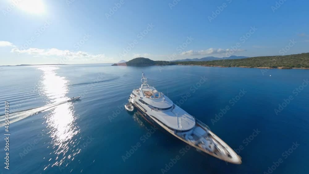 FPV video, view from above, stunning aerial view from an FPV drone flying at high speed over a blue water with some luxury yachts sailing during a sunny day. Sardinia, Italy.