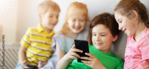 Group of children sitting indoors and looking in the smartphone