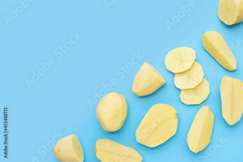 Raw peeled potatoes on blue background