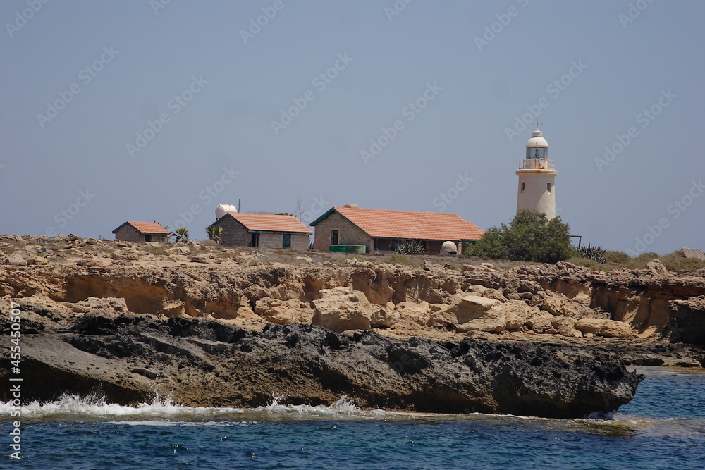 A lighthouse and small houses with tiled roofs on a stone cliff. High quality photo