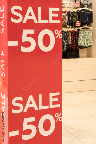 showcase with the text SALE in the shop on a red poster. sale in shopping window of fashion store