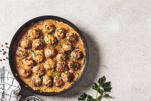 Swedish meatballs in creamy sauce in black frying pan, gray background. Scandinavian food concept. photo