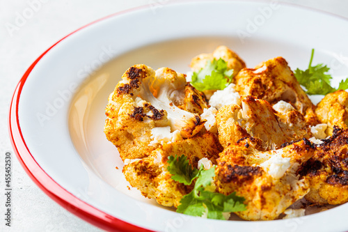 Spicy baked cauliflower with feta cheese in white plate. Vegetarian food concept.
