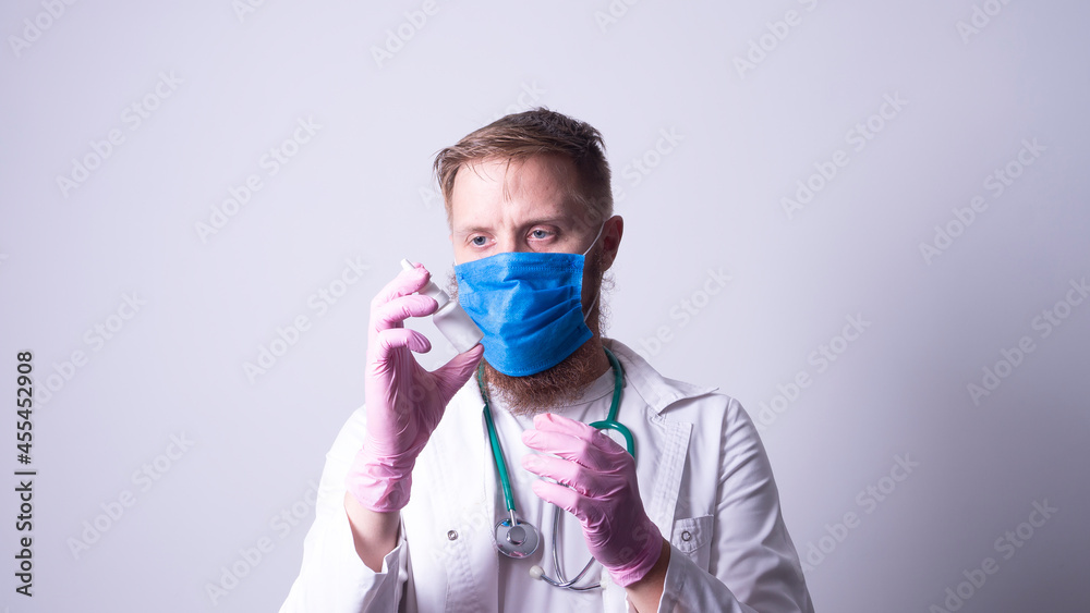 a young doctor in a mask holds a remedy for the common cold a young doctor in a mask holds a remedy for the common cold