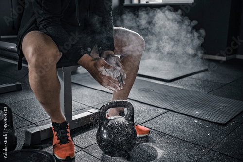 Sports background. Young athlete getting ready for crossfit training. Powerlifter hand in talc preparing to bench press.
