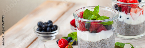 Vegan low calories chia seed pudding with fresh organic berries, plant milk, mint. Concept of dieting, detox, tasty simple super food, healthy sweet desserts. Banner. Wooden background