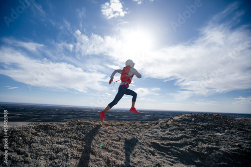Woman trail runner cross country running on sand desert mountain top