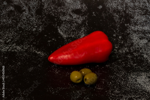 fresh sweet peppers and olives on dark background
