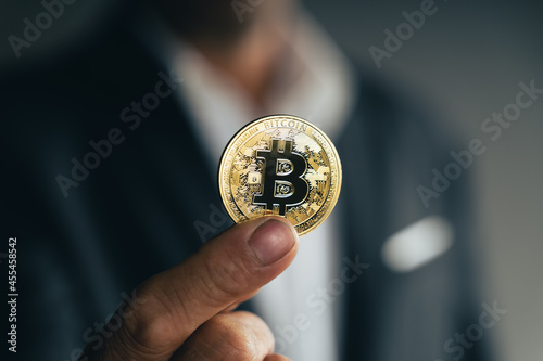 Handsome Investor Businessman in black suit holding a golden bitcoin on dark background, trading, Cryptocurrency, Digital virtual currency, alternative finance and investment Concept..