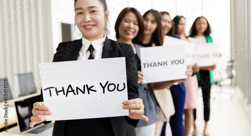 Group of businesspeople join together greeting and hold thank you word for sign of thankfulness to someone in modern office. Idea for good teamwork feeling declaration and support for colleagues © Bangkok Click Studio