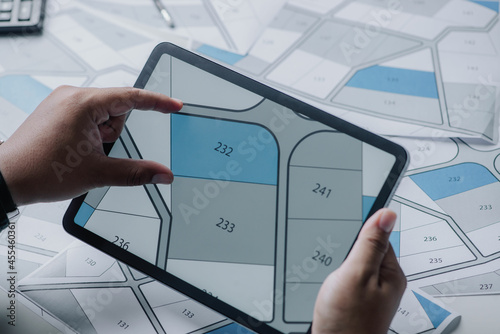 Man searching building plot to buy on cadastral plan for house construction on digital tablet. house or residential i.e. construction, development, sale, buy.. photo