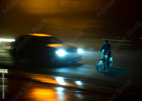 Dangerous city traffic situation with cyclist and car in the city at night