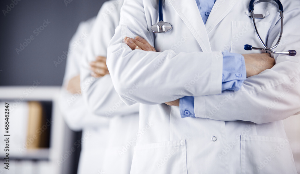 Group of modern doctors standing as a team with arms crossed in sunny hospital and ready to help patients. Medical help, insurance in health care Group of modern doctors standing as a team with arms crossed in sunny hospital and ready to help patients. Medical help, insurance in health care
