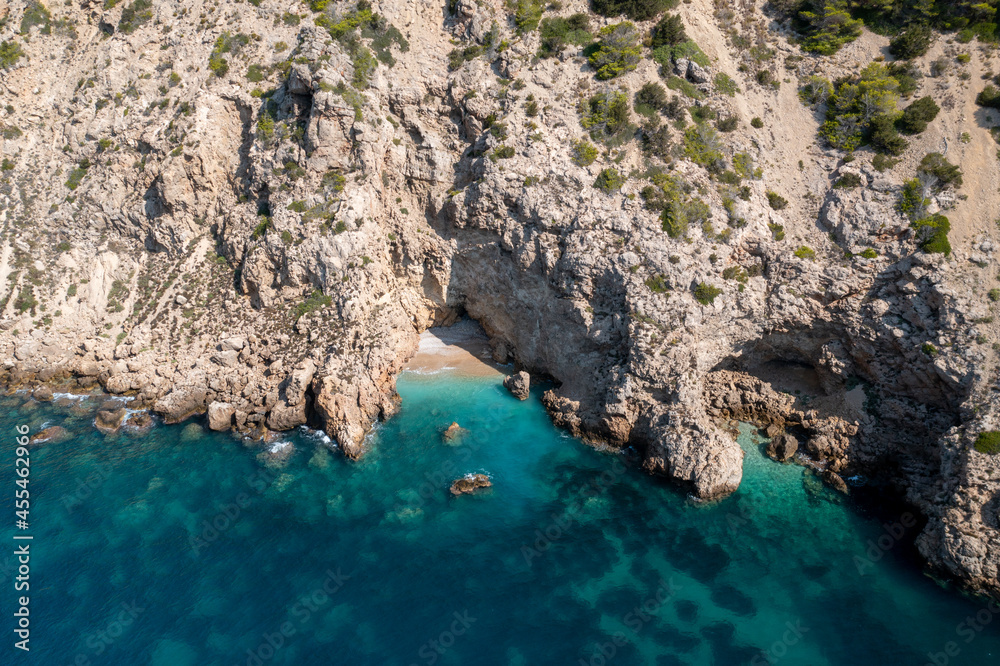 Aerial photo of the Spanish island of Ibiza showing a private secluded beach near the beach at Cala Llonga in the summer time in the Balearic Islands, Spain