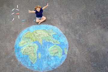 Little preschool girl with earth globe painting with colorful chalks on ground. Positive toddler child. Happy earth day concept. Creation of children for saving world, environment and ecology.