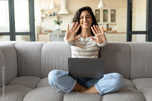 Take a break. Happy young lady with laptop directing both palms at camera, making pause in online work at home