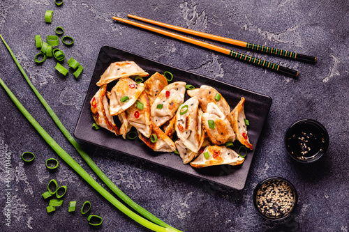 Fried dumplings served with green onions, sesame seeds and chili peppers