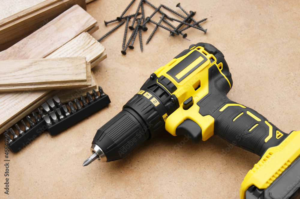 The yellow-black screwdriver on wood background, screws. The yellow-black screwdriver on wood background, screws.