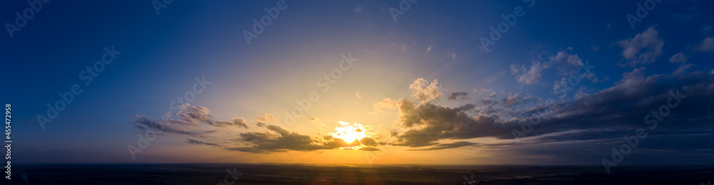 Panorama of sunrise and dark morning blue sky. Cloudy weather at dawn with bright orange sunlight