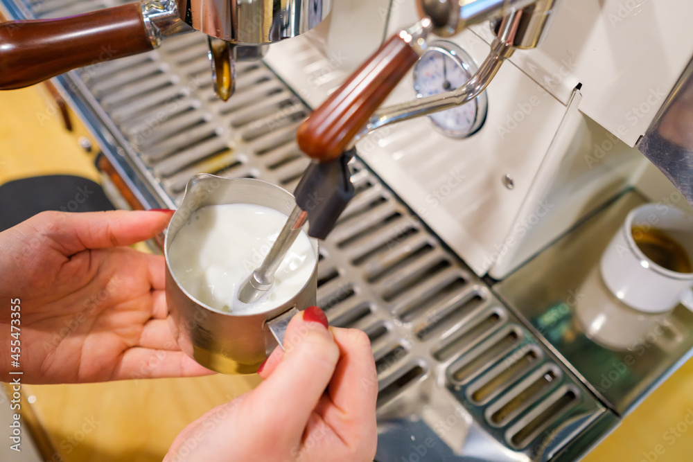 Barista whipping milk in coffee machine