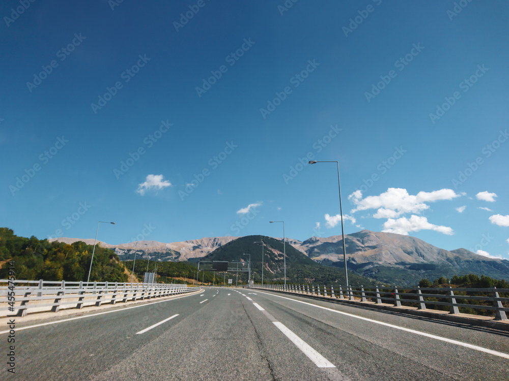 Fototapeta premium Driving highway mountain road in Greece on a sunny summer day with scenic cloudscape view