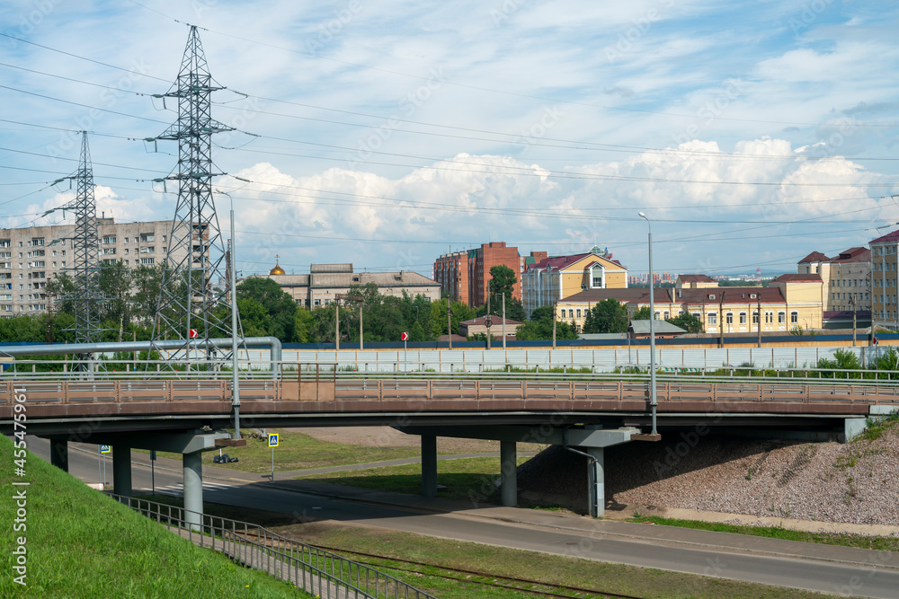 Massive car overpass in summer near the hills with houses. - obrazy, fototapety, plakaty 