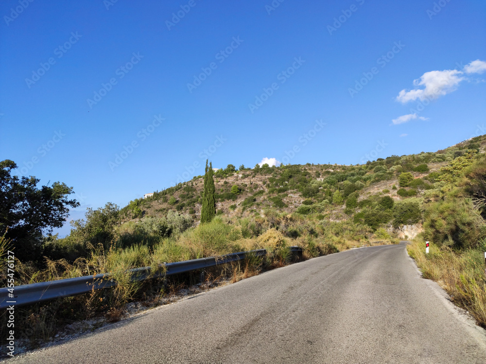 Driving mountain serpentine road with clear blue sky, Lefkada island, Ionian sea coast, Greece. Sunny summer scenic day trip
