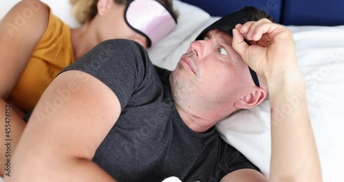 Surprised man picking up his sleep mask and looking at woman lying with him in bed 4k movie