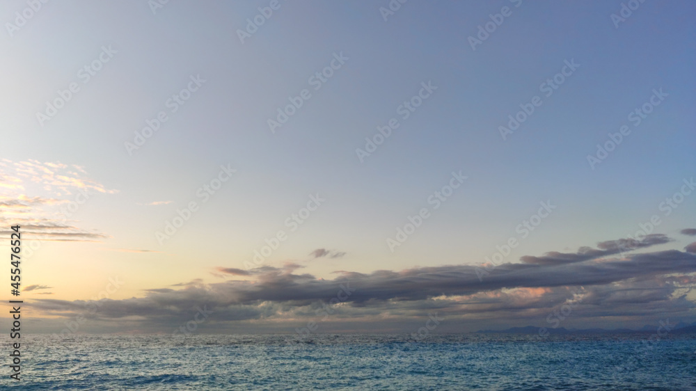 Sunset sky with dark purple clouds above blue rippled sea water. Dramatic cloudscape on Mediterranean sea