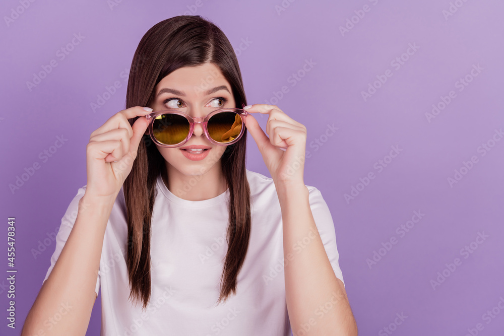 Photo of funny girl touch sunglasses look empty space isolated on violet background Photo of funny girl touch sunglasses look empty space isolated on violet background
