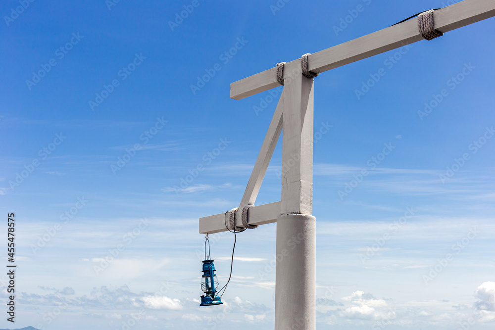 White wooden pole with lanterns hanging in a bright sky background. White wooden pole with lanterns hanging in a bright sky background.