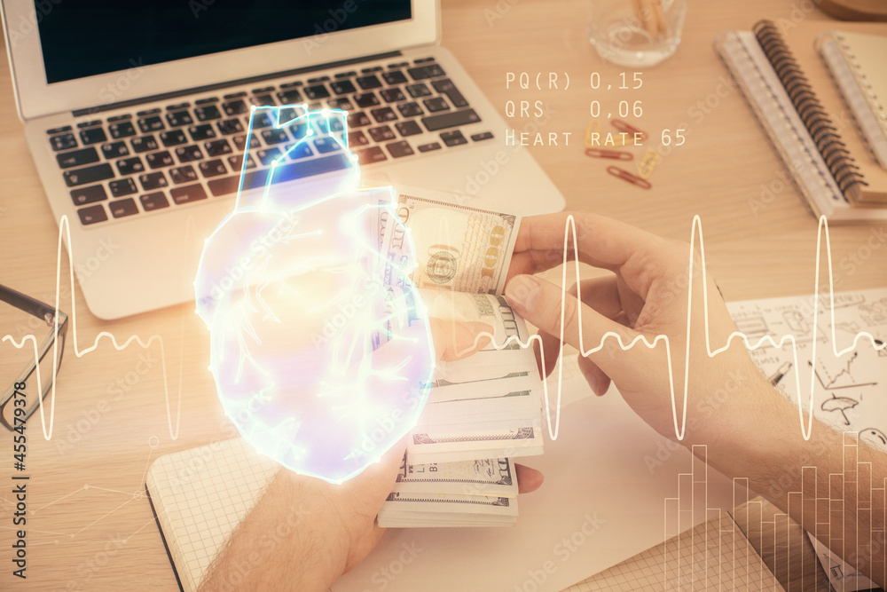 Multi exposure of heart drawing hologram and USA dollars bills and man hands. Medical education Multi exposure of heart drawing hologram and USA dollars bills and man hands. Medical education