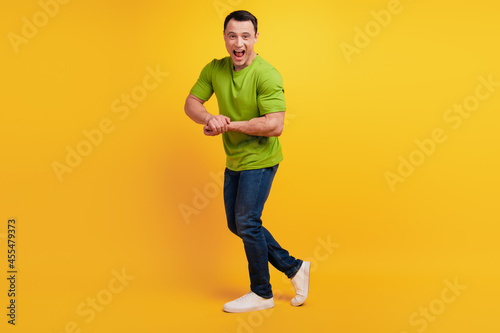 Portrait of crazy astonsihed brutal sportive guy show biceps hands on yellow wall