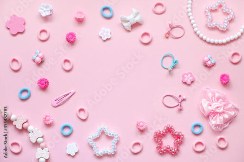 Girly desktop with stylish hair accessories on pink background. Copy space, flay lay, top view.
