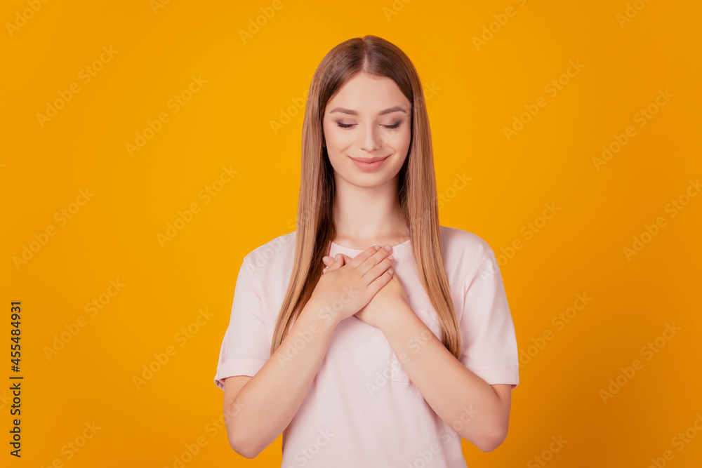 Portrait of thankful serene adorable lady hands chest close eyes on yellow background Portrait of thankful serene adorable lady hands chest close eyes on yellow background