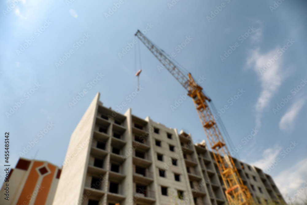 Blurred view of unfinished building and construction crane outdoors