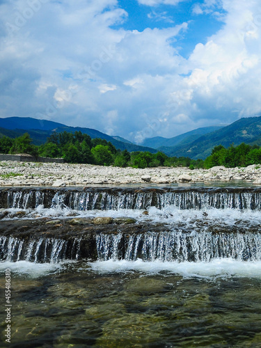 A stepped waterfall built in Gilort river s bed. Rainy summer day. The large valley is covered with boulders. Carpathia  Romania