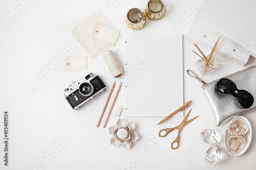 female accessories on white background. Flat lay, top view desk with sketchbook, jewelry, photo camera. open blank notebook with copy space for text