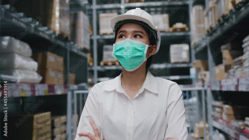 Asian woman inspector wearing safety hardhat and Face mask to prevent COVID-19 in warehouse. Worker in Factory safety measure and keeping distance from work. Concept Blue collar health Asian woman inspector wearing safety hardhat and Face mask to prevent COVID-19 in warehouse. Worker in Factory safety measure and keeping distance from work. Concept Blue collar health
