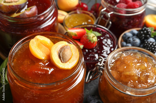 Fototapeta Naklejka Na Ścianę i Meble -  Jars with different jams and fresh fruits on table, closeup